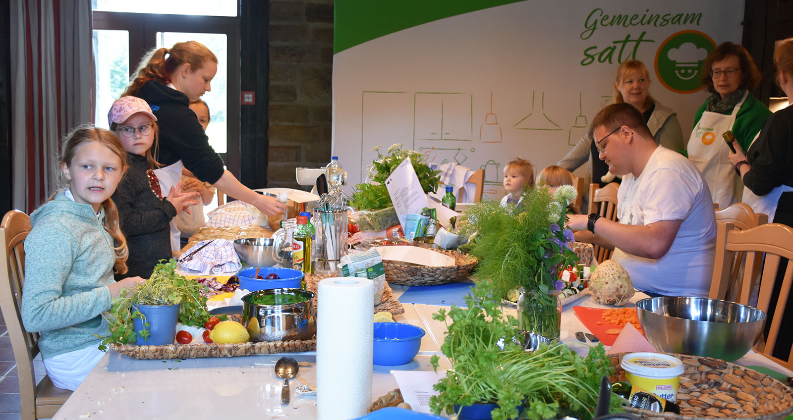 Gemeinsam satt Eine Gruppe Kinder kocht am grün geschmückten Gemeinsam Satt-Tisch