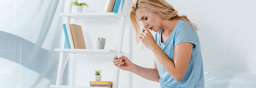 junge Frau nimmt Nasenspray