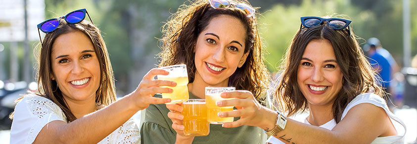 Drei junge Frauen prosten sich mit Bier zu.