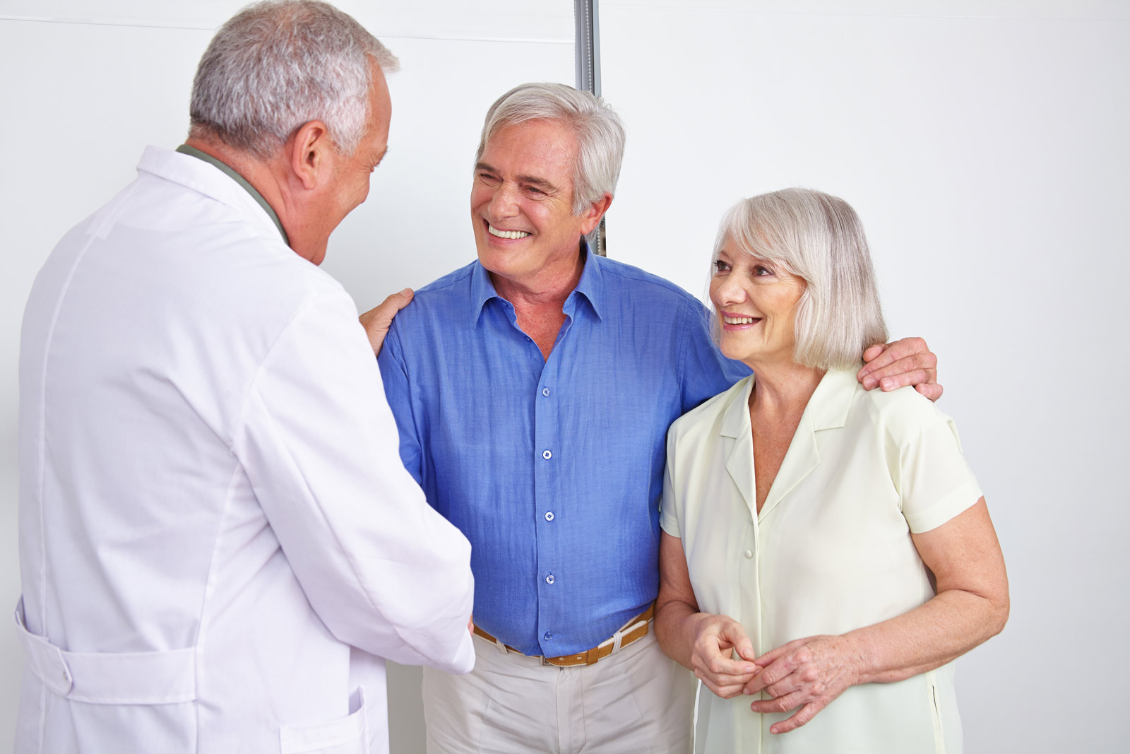 Ein älteres Paar glücklich beim Handshake mit dem Arzt